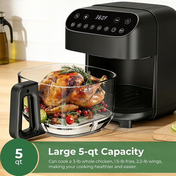Black air fryer with a cooked chicken inside on a wooden countertop.