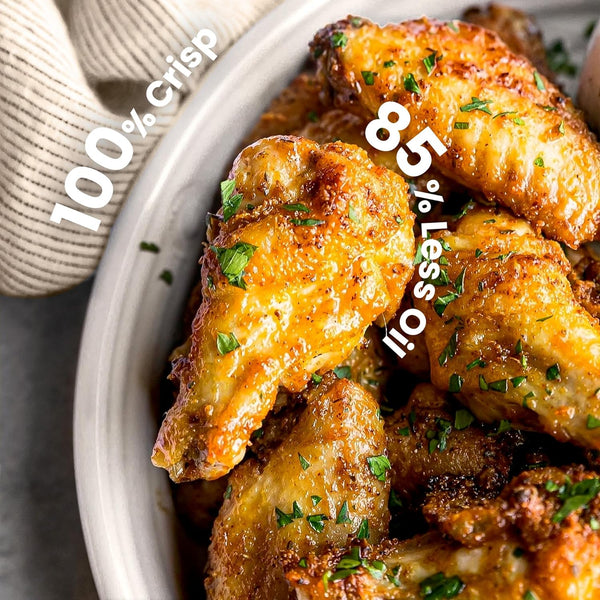 Baked chicken wings with text indicating crispiness and oil reduction on a white plate.
