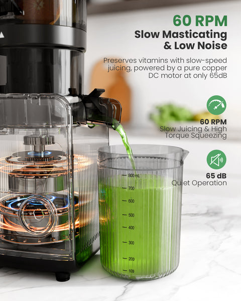 Juicer with a measuring cup filled with green juice on a white countertop.