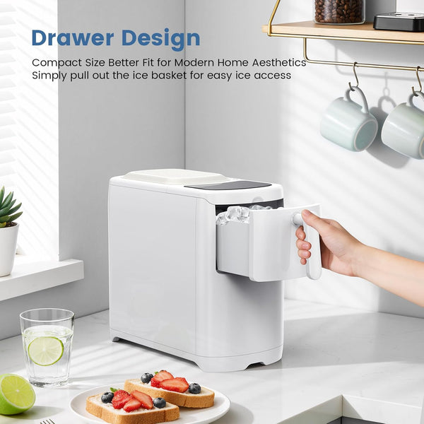 White ice maker on a kitchen counter with a hand pulling out an ice basket, surrounded by a glass of water, a lime, and toast with berries.