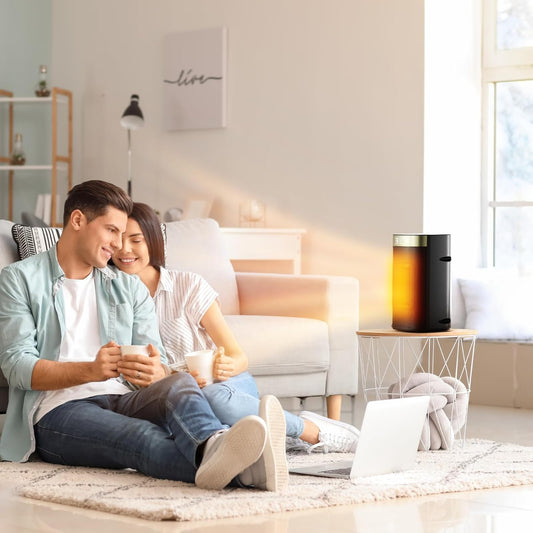 Couple sitting on a couch in a living room with a coffee maker on a side table.